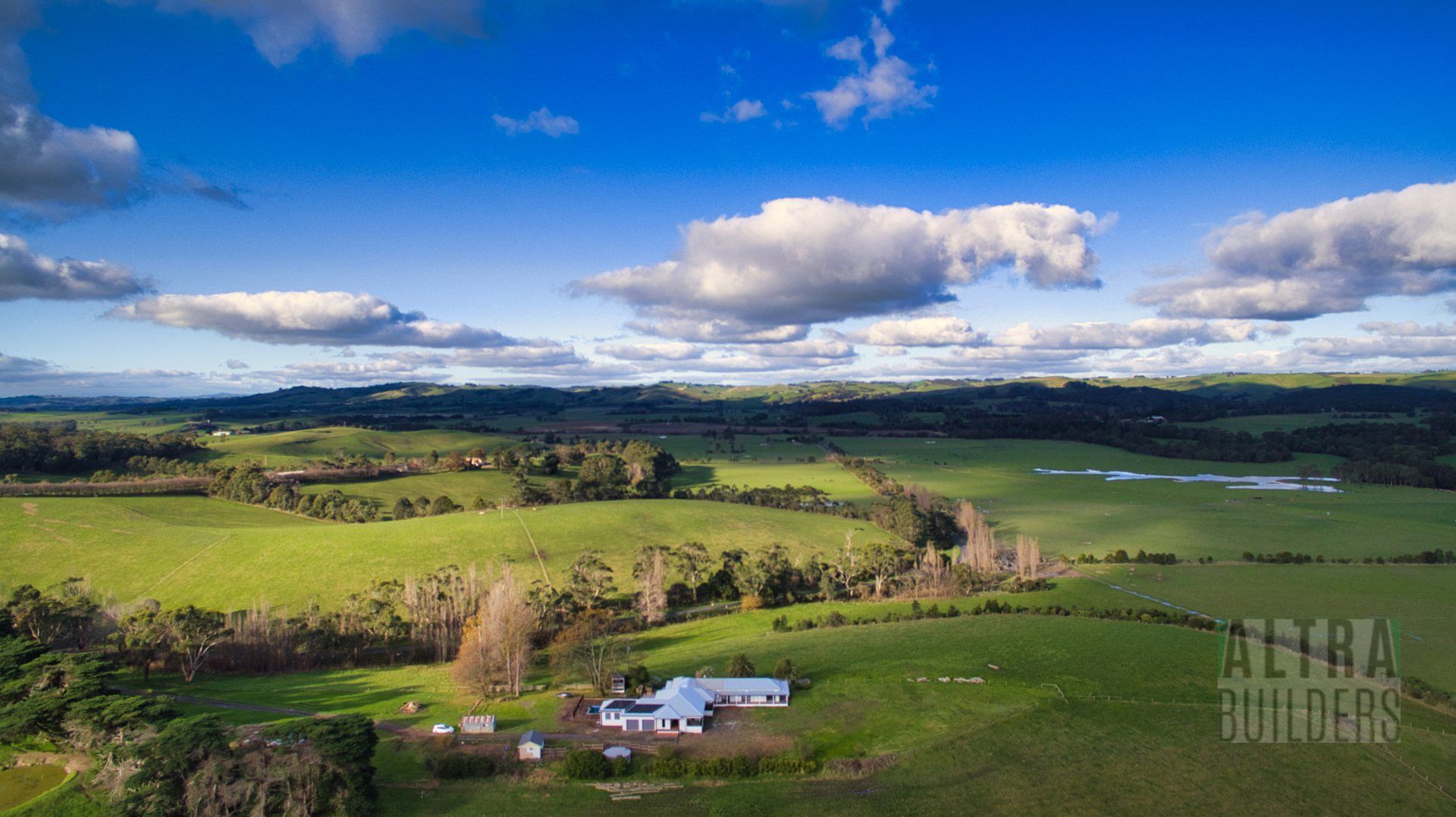 An aerial view of a farm with a house in the middle of a lush green field.