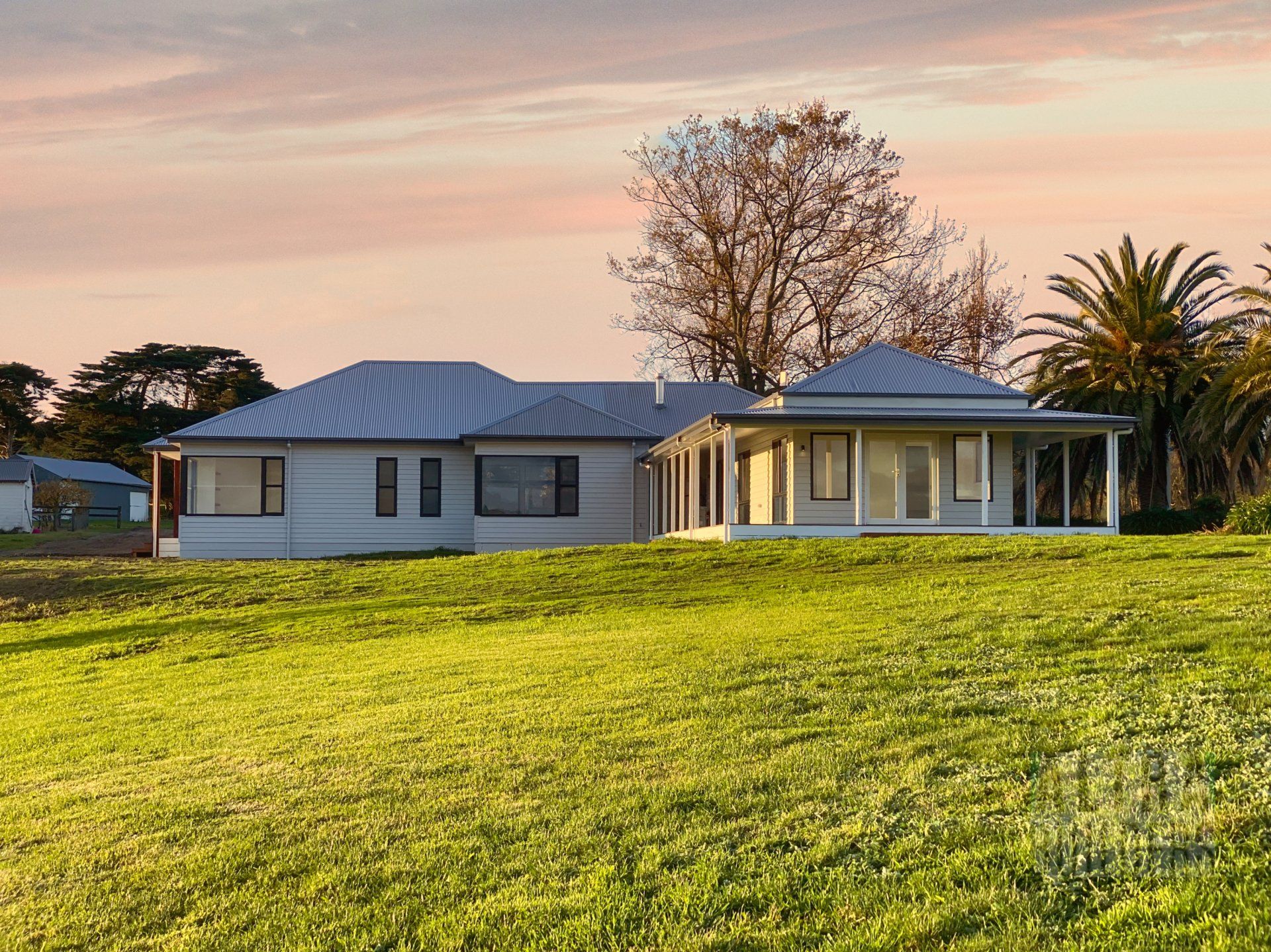 A white house sits in the middle of a lush green field