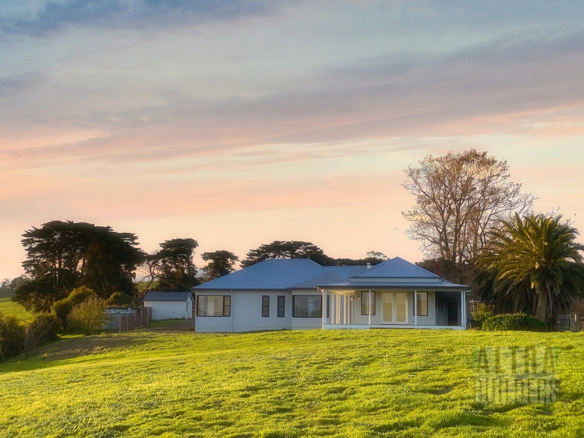 A white house sits on top of a grassy hill