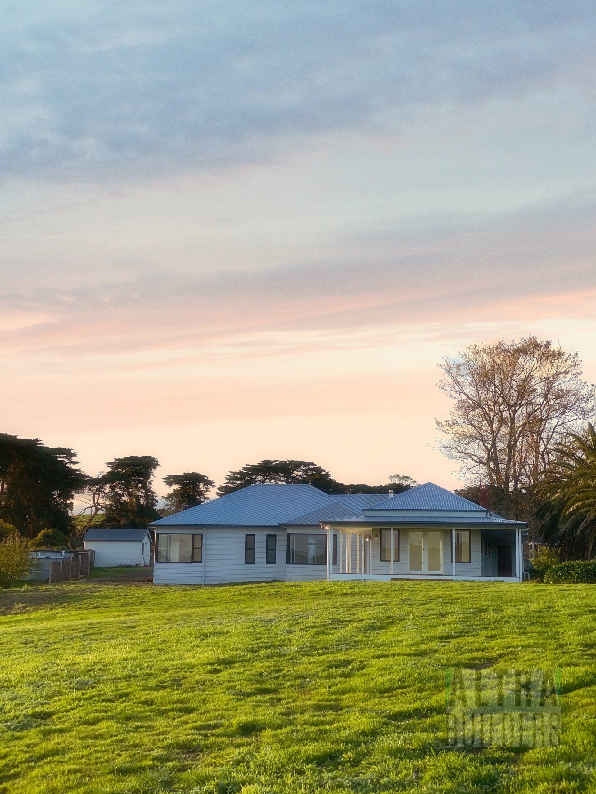 A white house sits in the middle of a grassy field