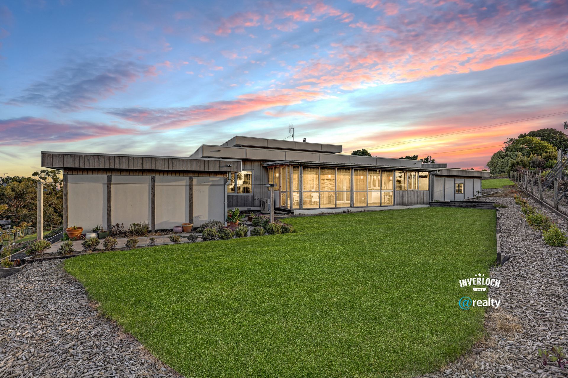 A large house with a lot of windows is sitting on top of a lush green field.