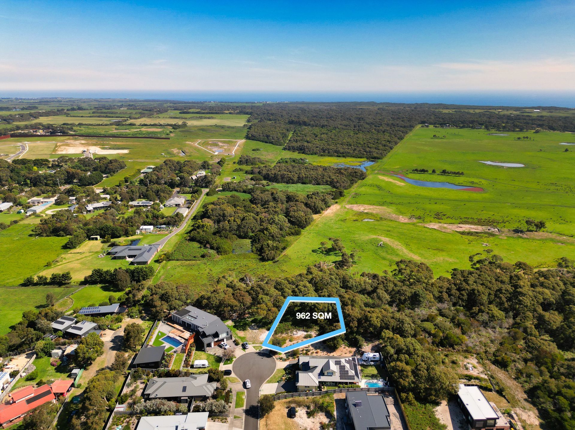 An aerial view of a house in the middle of a lush green field