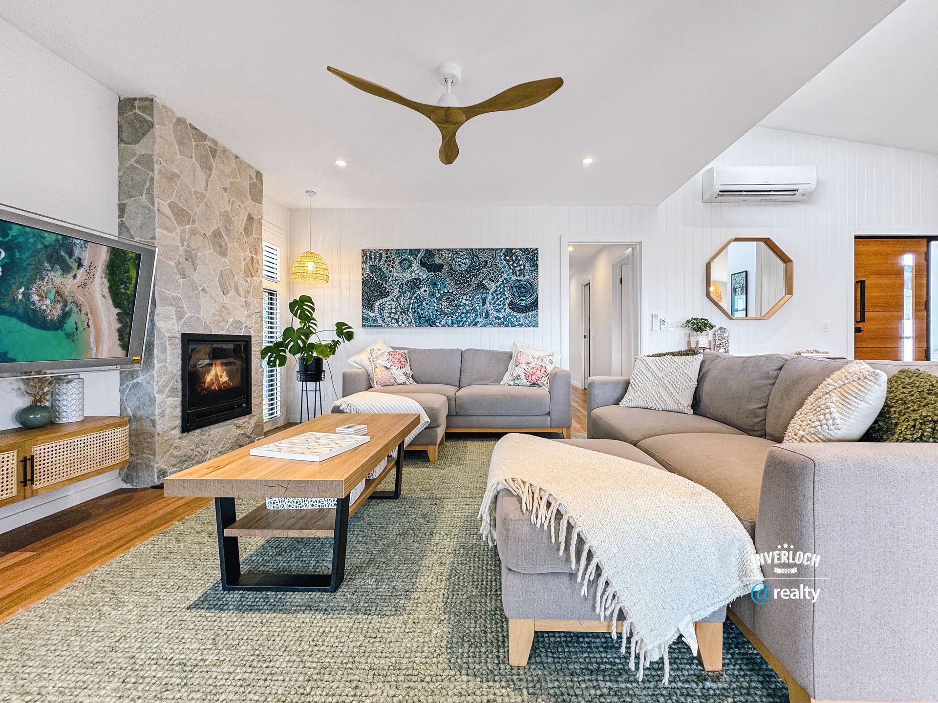 A living room with a couch , coffee table , fireplace and ceiling fan.