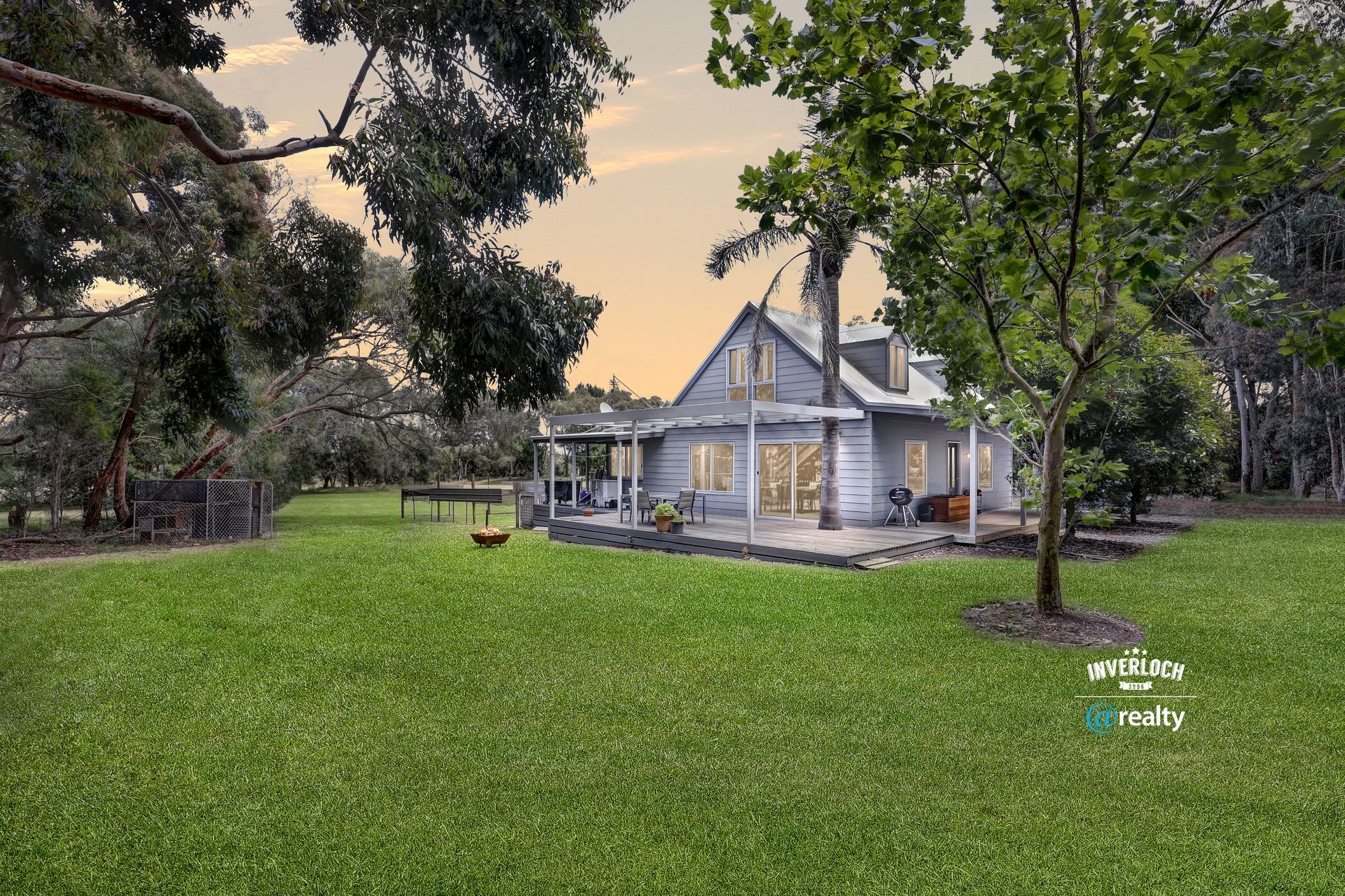A white house is sitting in the middle of a lush green field surrounded by trees.