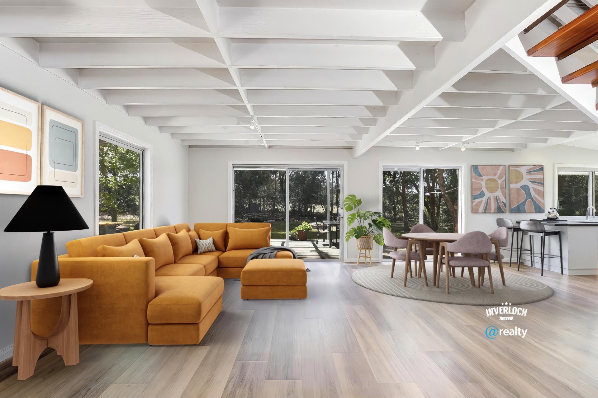 Open-plan living space with a mustard sectional sofa, dining area, and large windows with outdoor views.