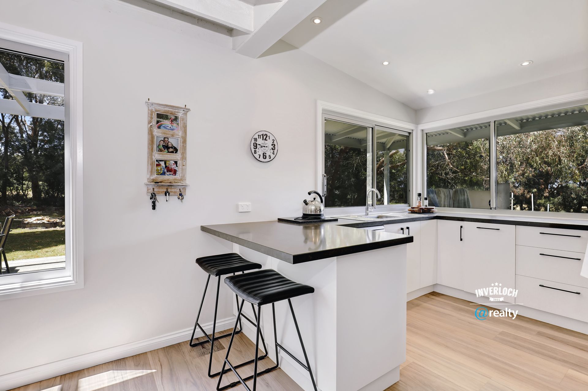 A kitchen with white cabinets , granite counter tops , and stools.