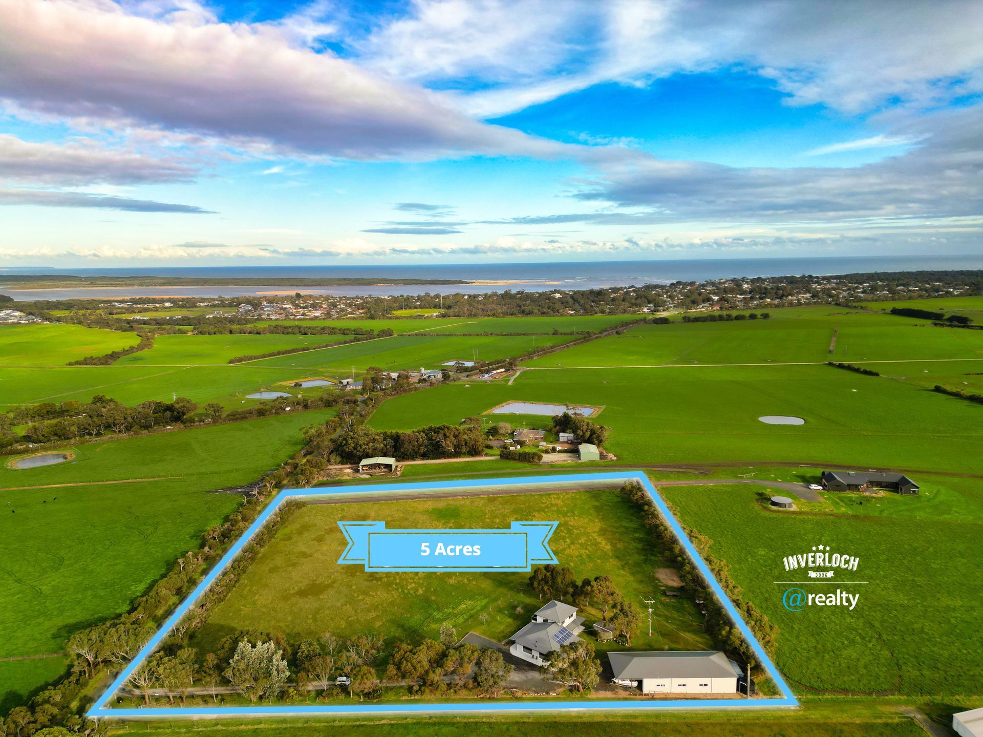 An aerial view of a large green field with a house in the middle.