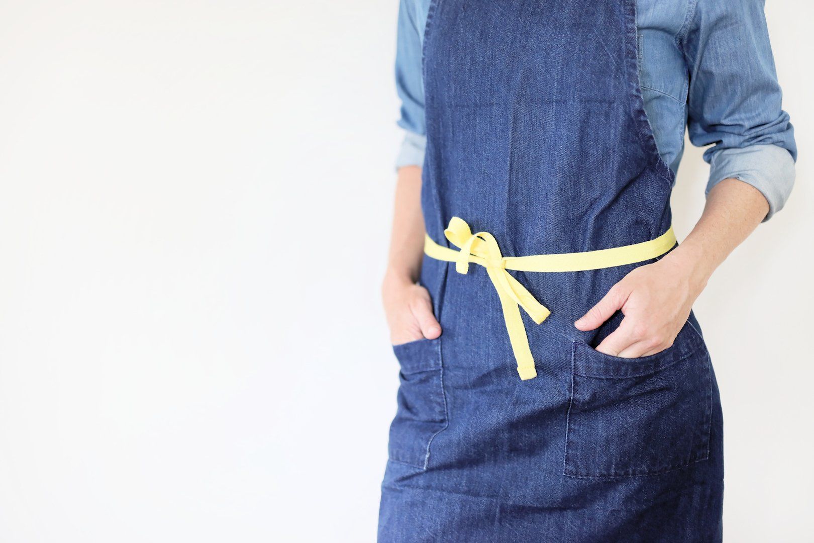 A woman wearing a blue apron with a yellow ribbon around her waist.