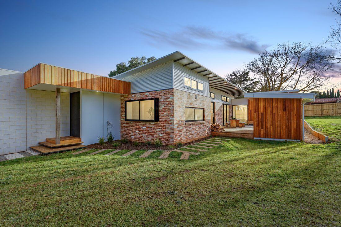 A modern house with a brick facade is sitting on top of a lush green field.