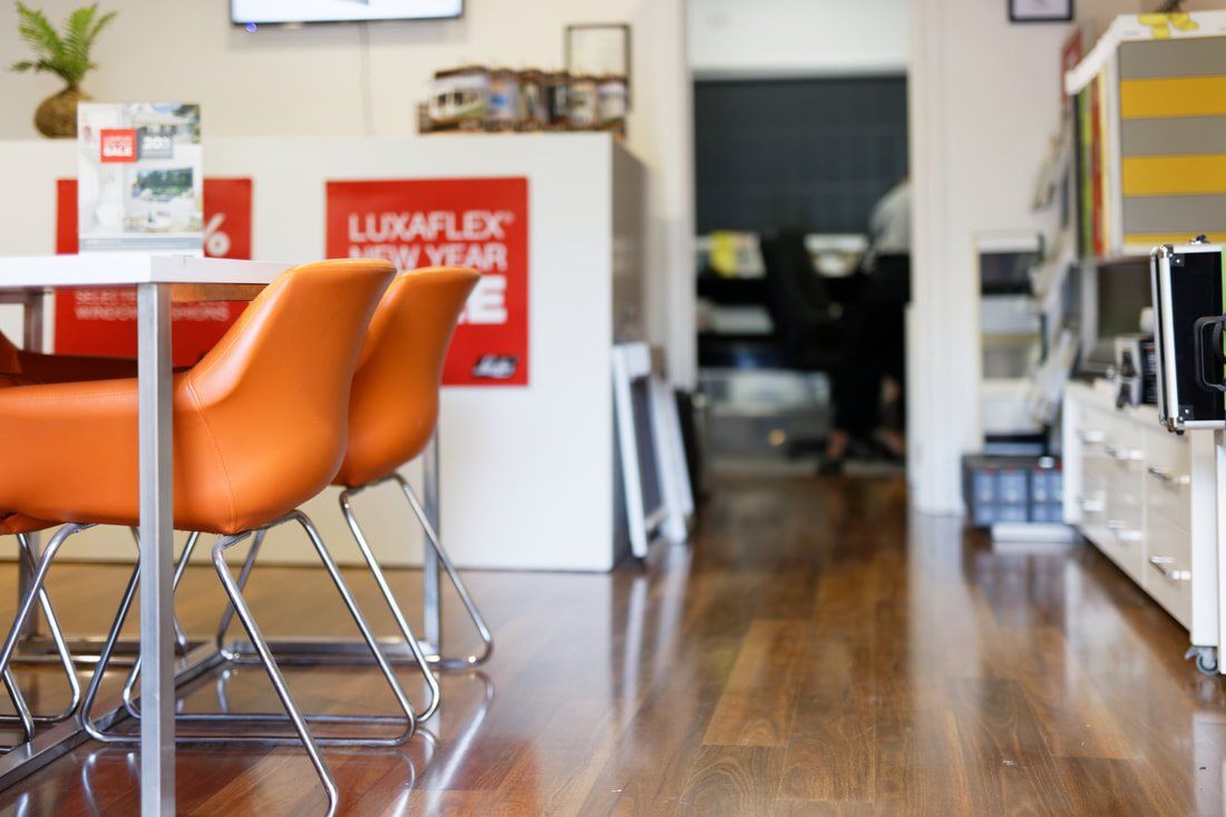 A room with a table and chairs and a sign that says luxaflex