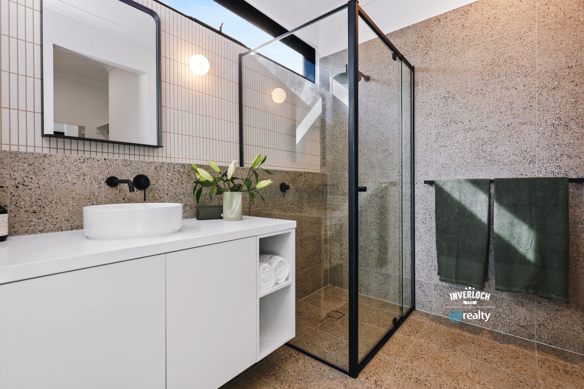 A bathroom with a sink , mirror , and walk in shower.