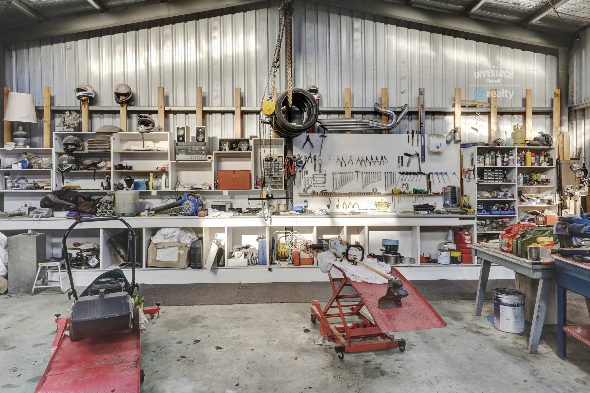 A garage filled with lots of tools including a motorcycle lift