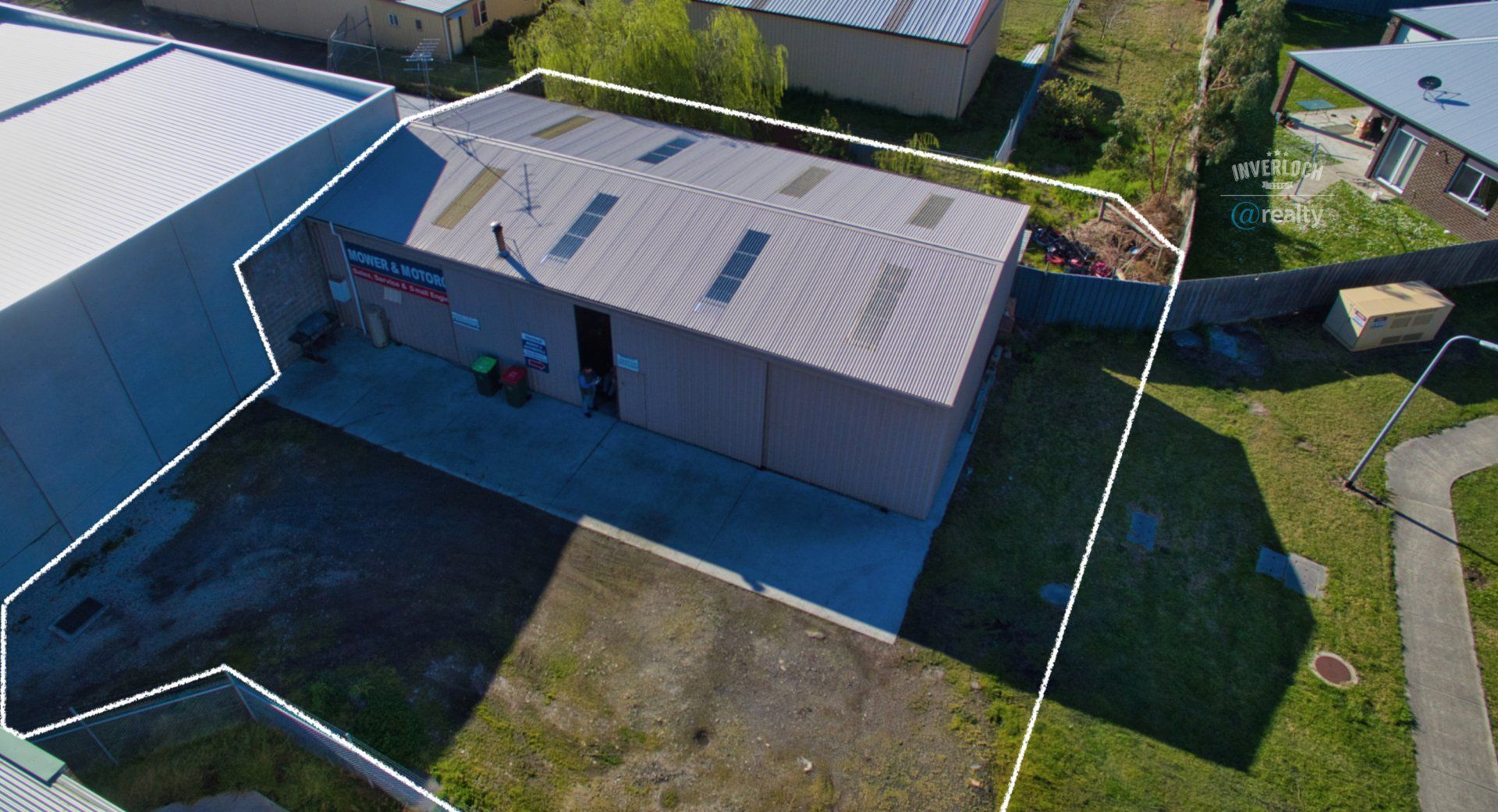 An aerial view of a building with a fence around it and a lot of grass.