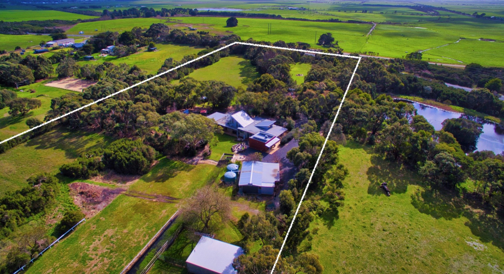 An aerial view of a lush green field with a house in the middle.