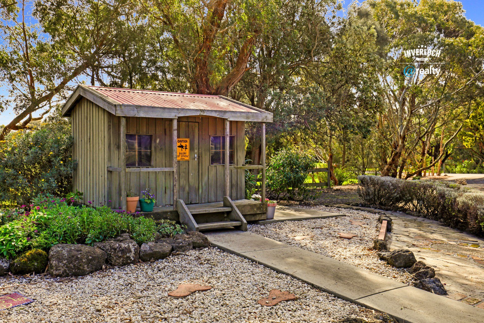 A small wooden house is sitting in the middle of a gravel yard.
