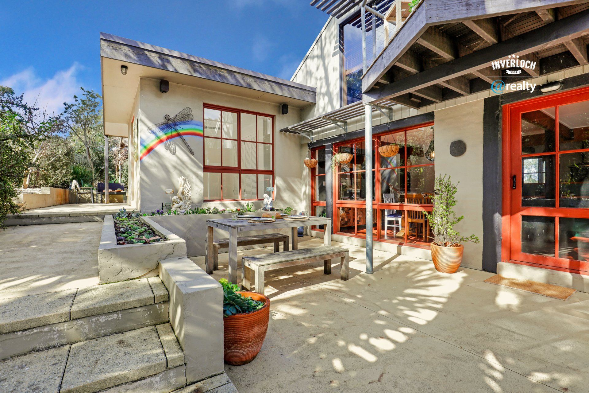 A large house with a patio with a table and benches in front of it.
