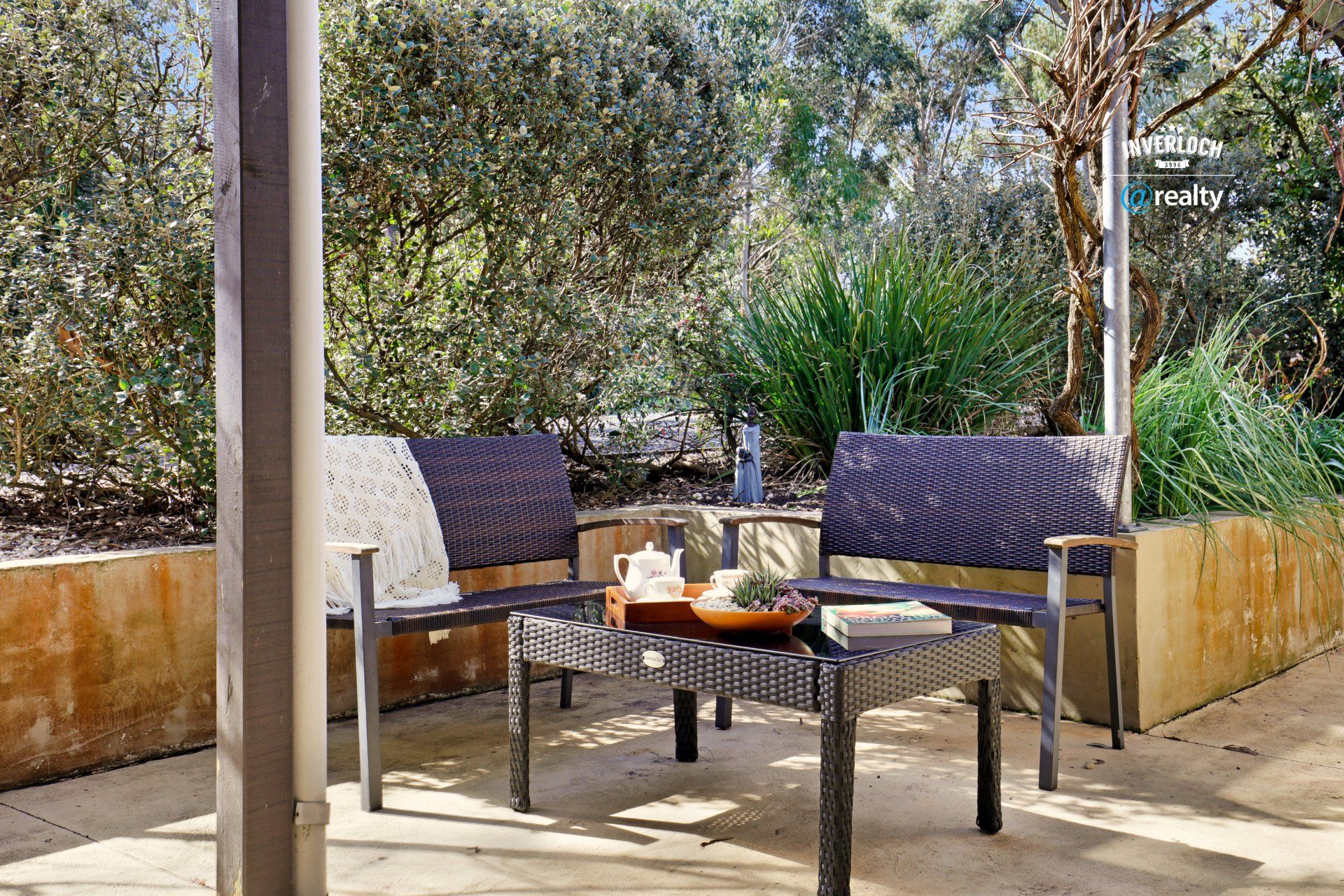 A patio with a table and chairs and trees in the background