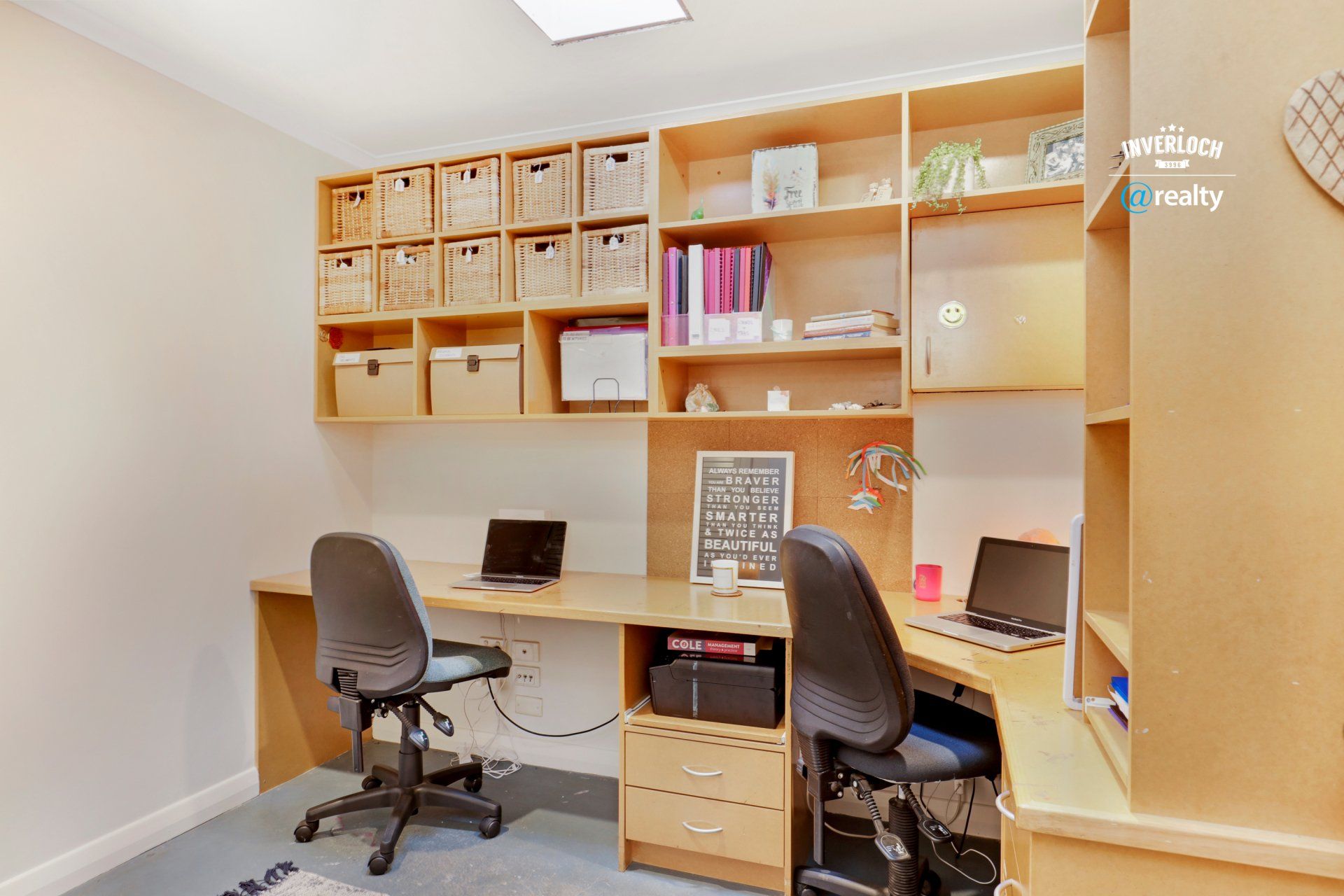 A room with two desks and two chairs and a clock on the wall.