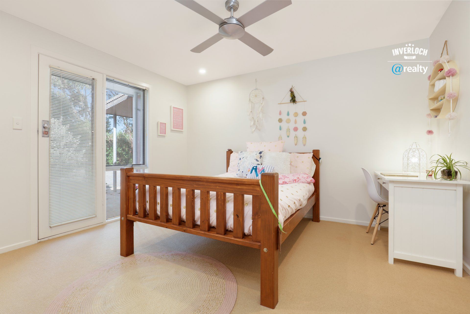 A bedroom with a bed , desk and ceiling fan.