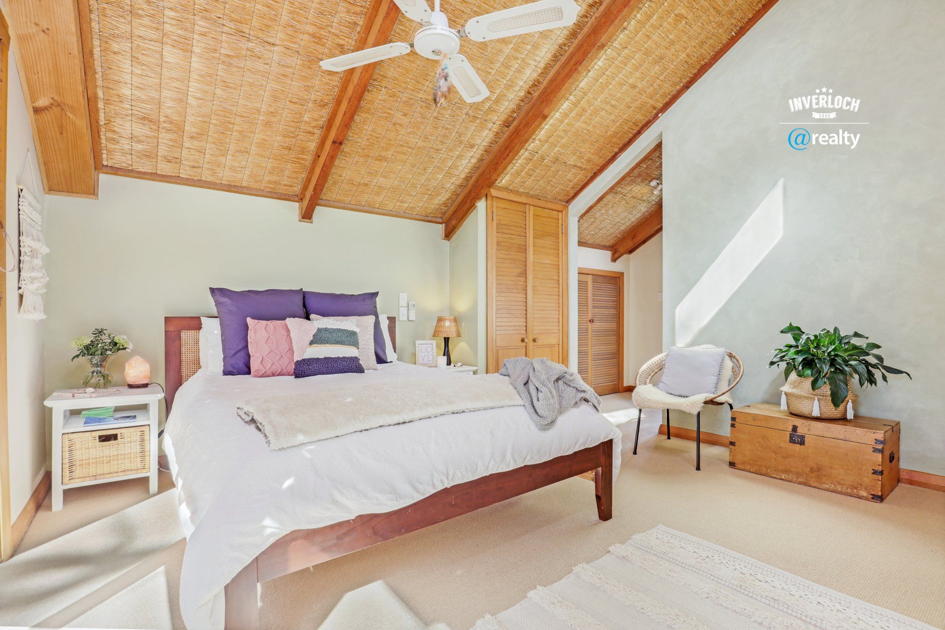 A bedroom with a bed , nightstand , chair and ceiling fan.
