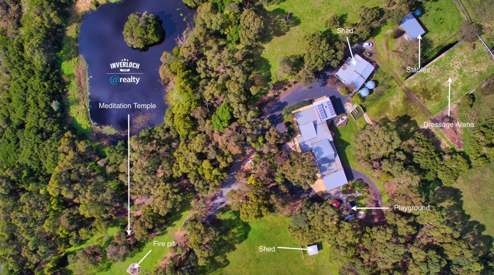 An aerial view of a house surrounded by trees and a lake.