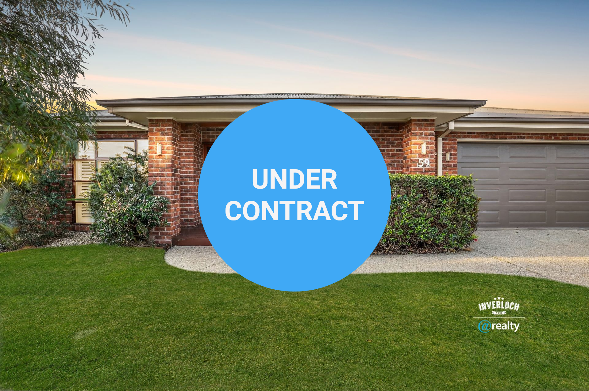 Brick house with green lawn, shrubs, and a closed garage door under a dusky sky.