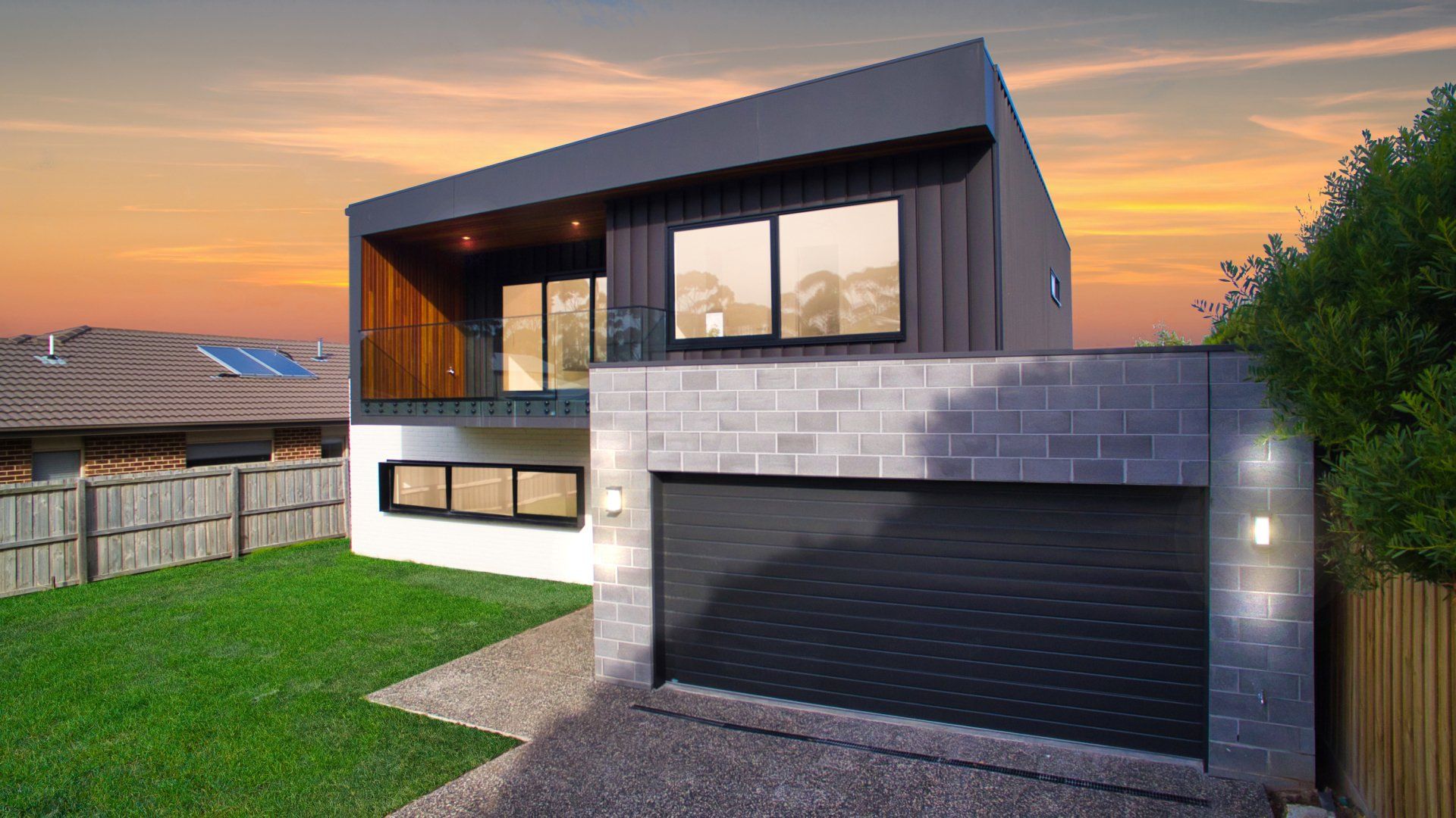 A modern house with a garage and a fence in front of it.
