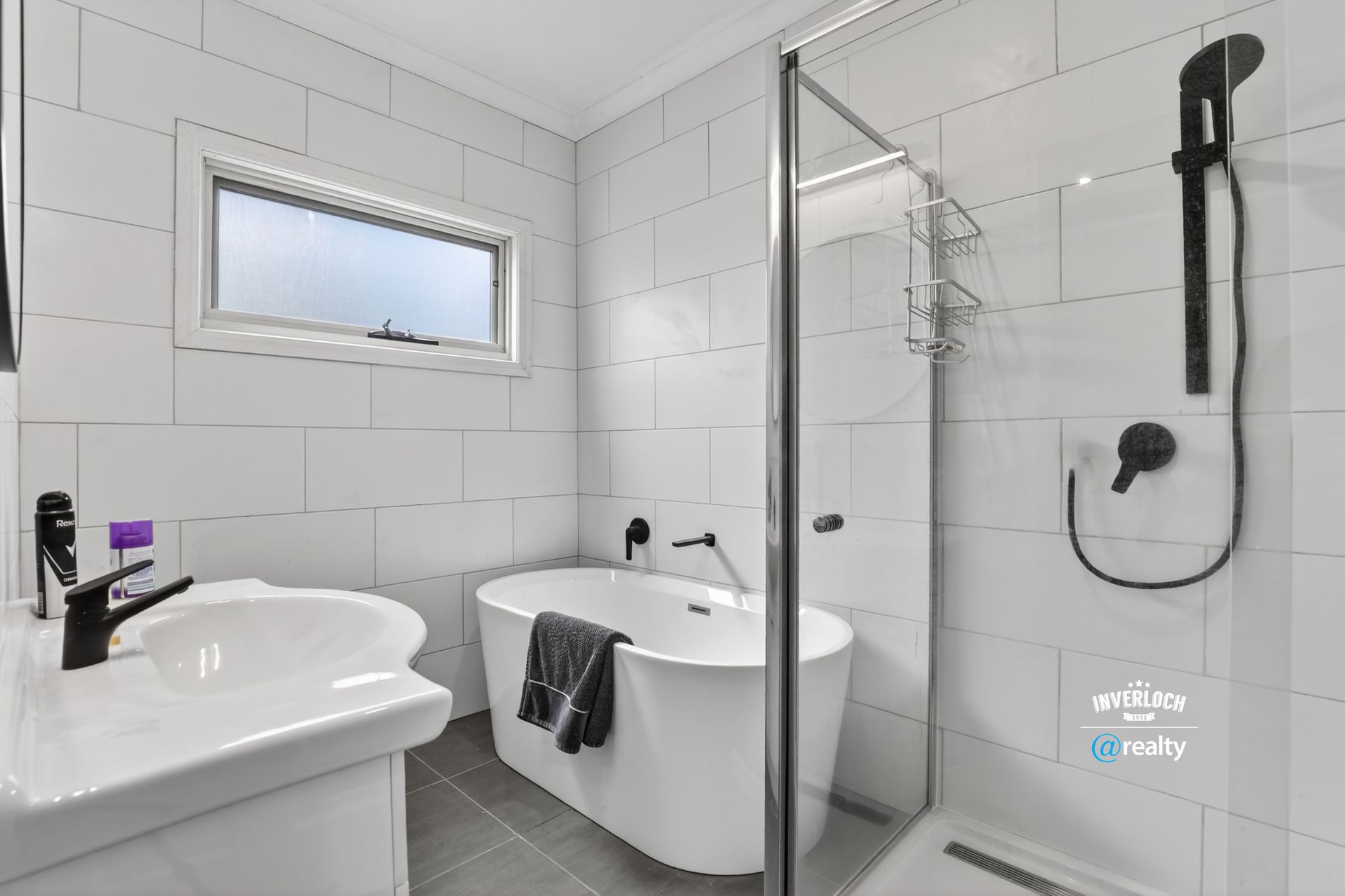 White bathroom with a freestanding tub, glass shower, and black fixtures.