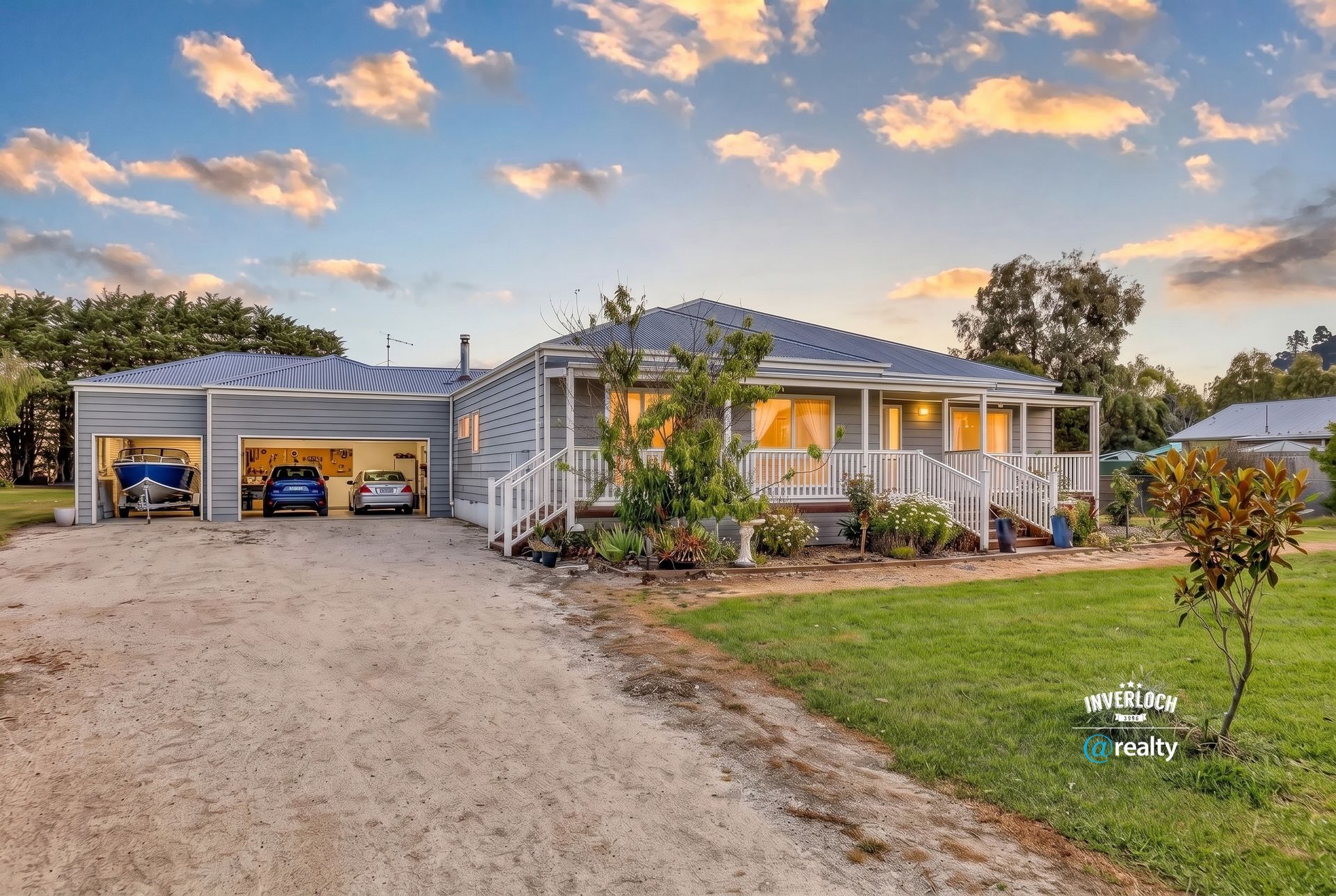 Single-story house with a covered porch, detached garage, and gravel driveway at sunset