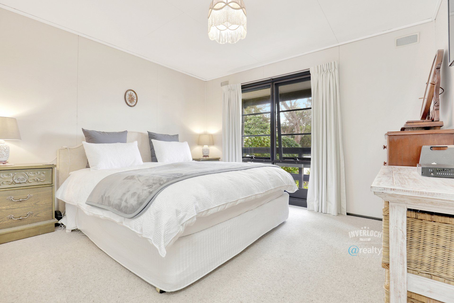 A bedroom with a large bed , dresser , nightstand and sliding glass doors.