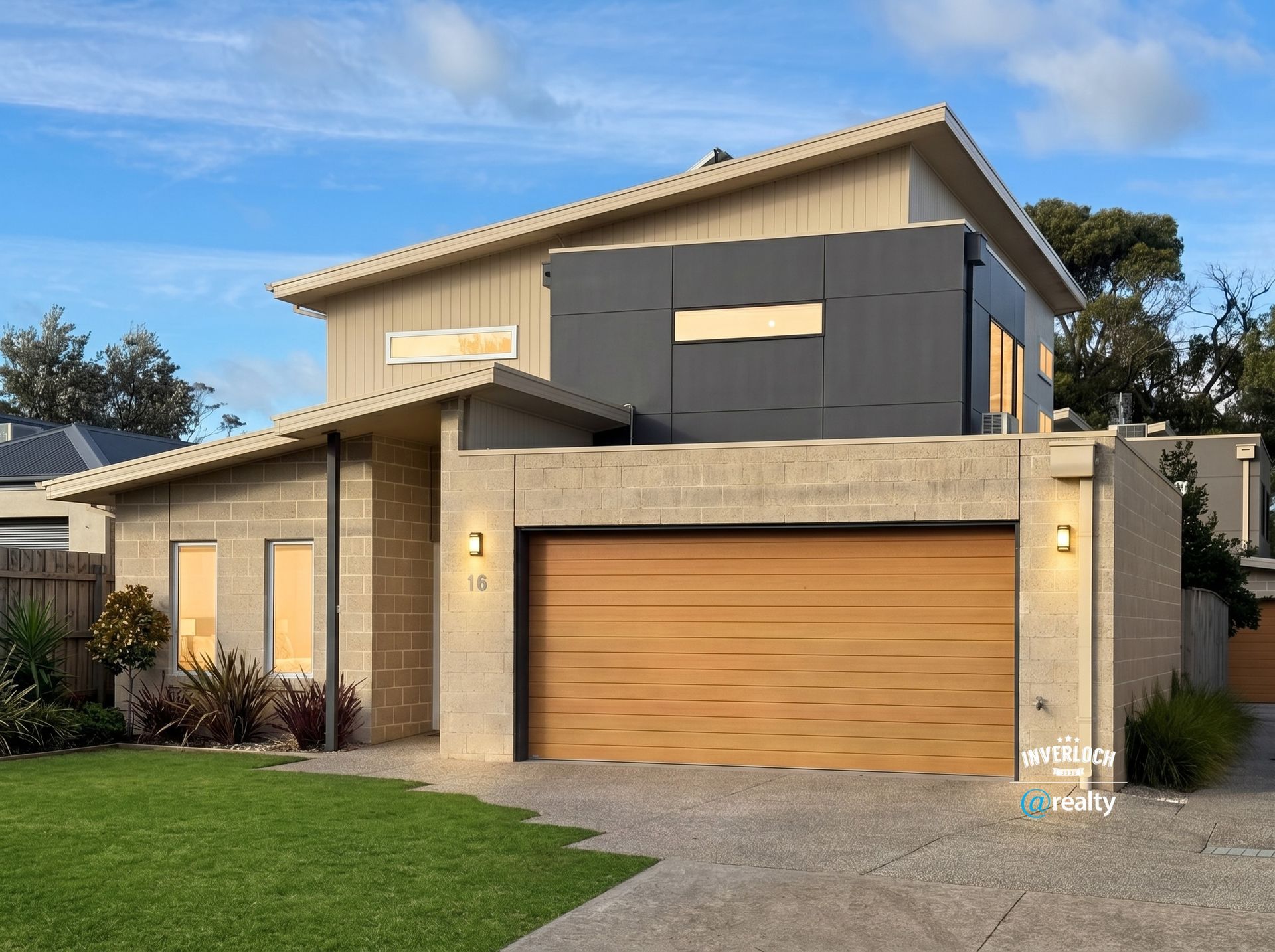 Modern two-story house with beige and gray exterior, large garage, and manicured lawn under a blue sky