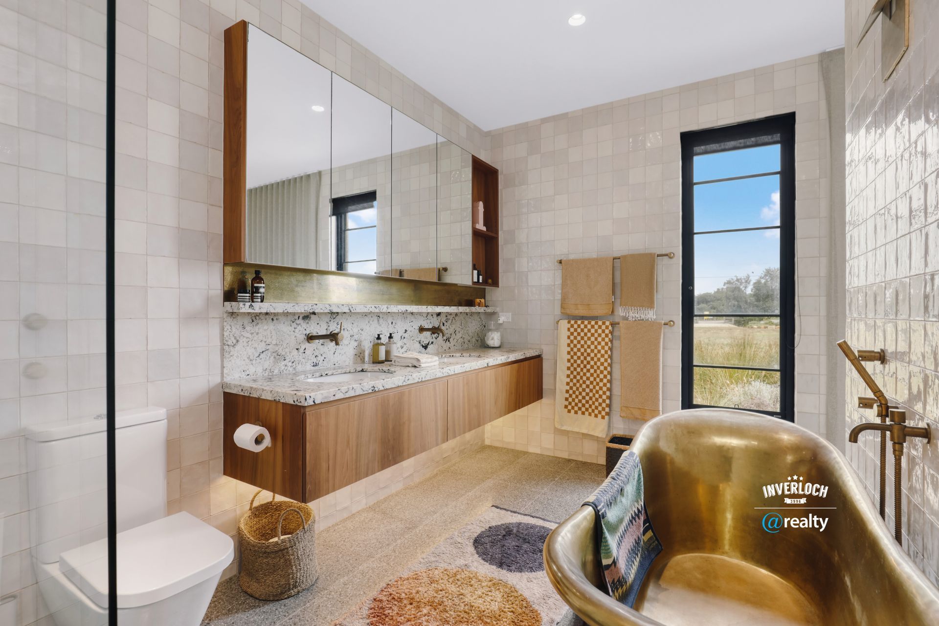 Modern bathroom with a gold bathtub, wood vanity, and patterned tile.