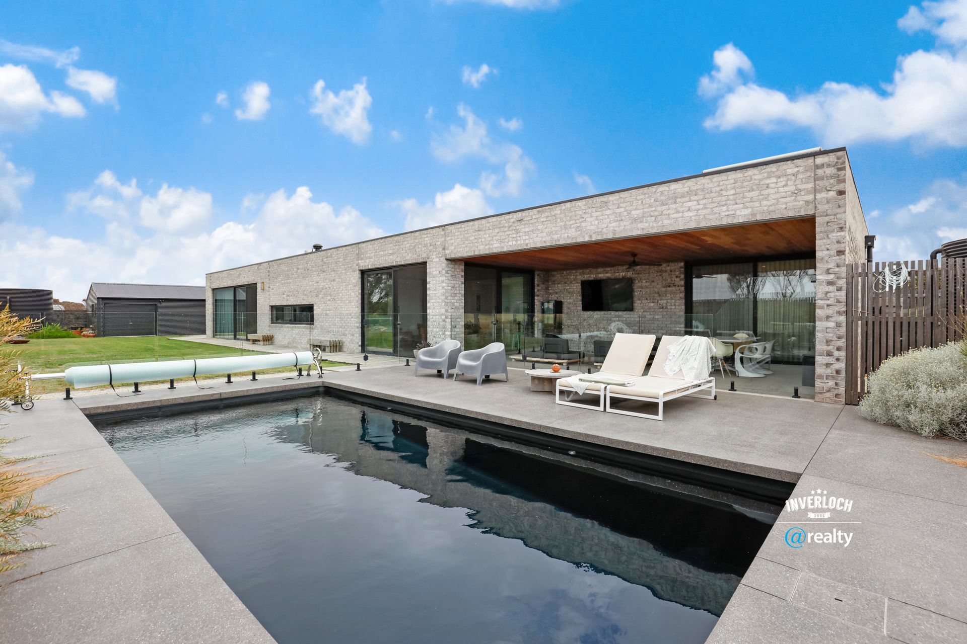 Modern house with pool and outdoor seating area on a sunny day.