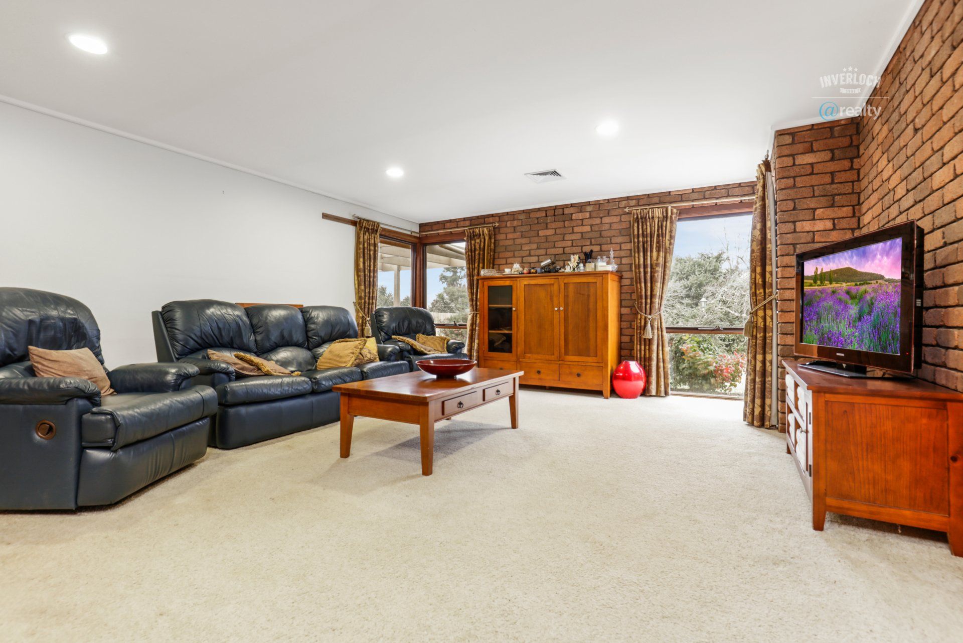 A living room with a couch , chairs , coffee table and television.