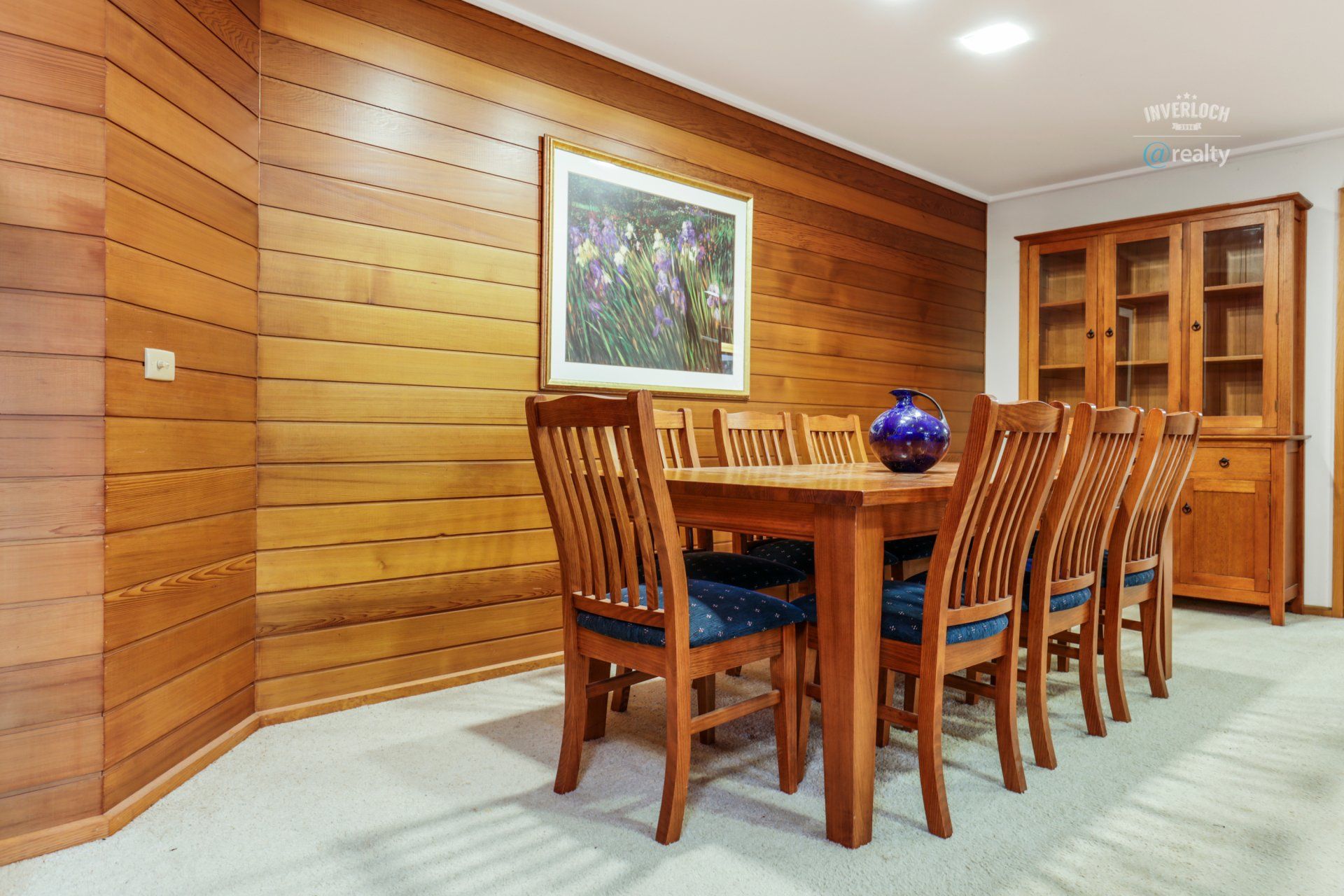 A dining room with a table and chairs and a picture on the wall