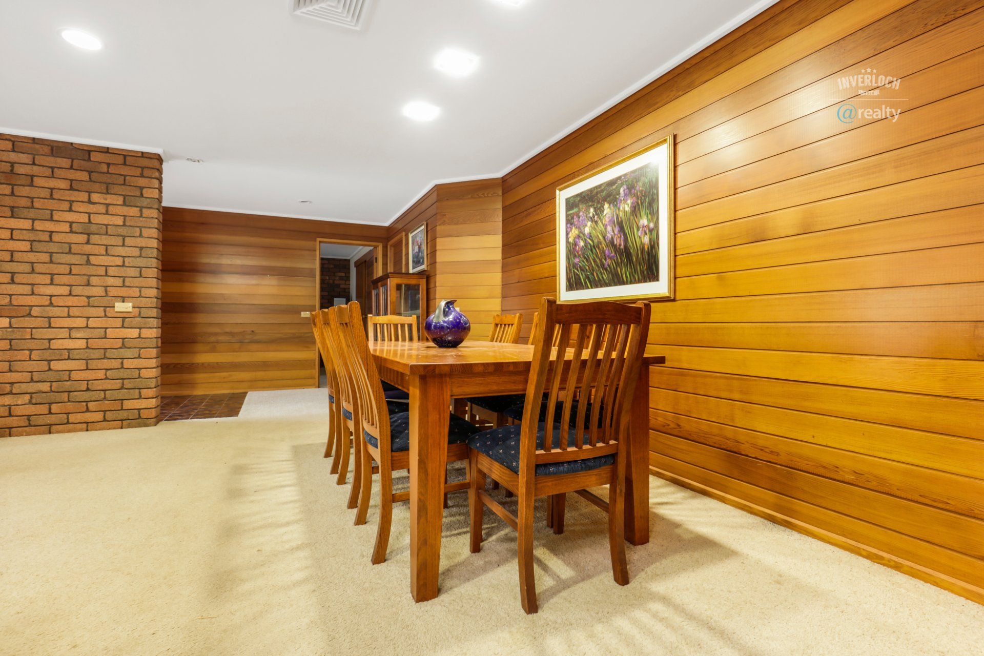 A dining room with a wooden table and chairs and a brick wall.