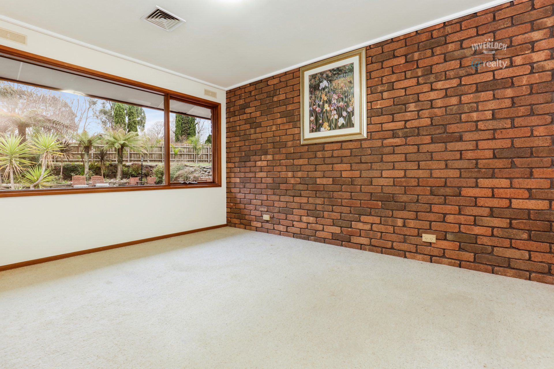 An empty room with a brick wall and a picture on the wall