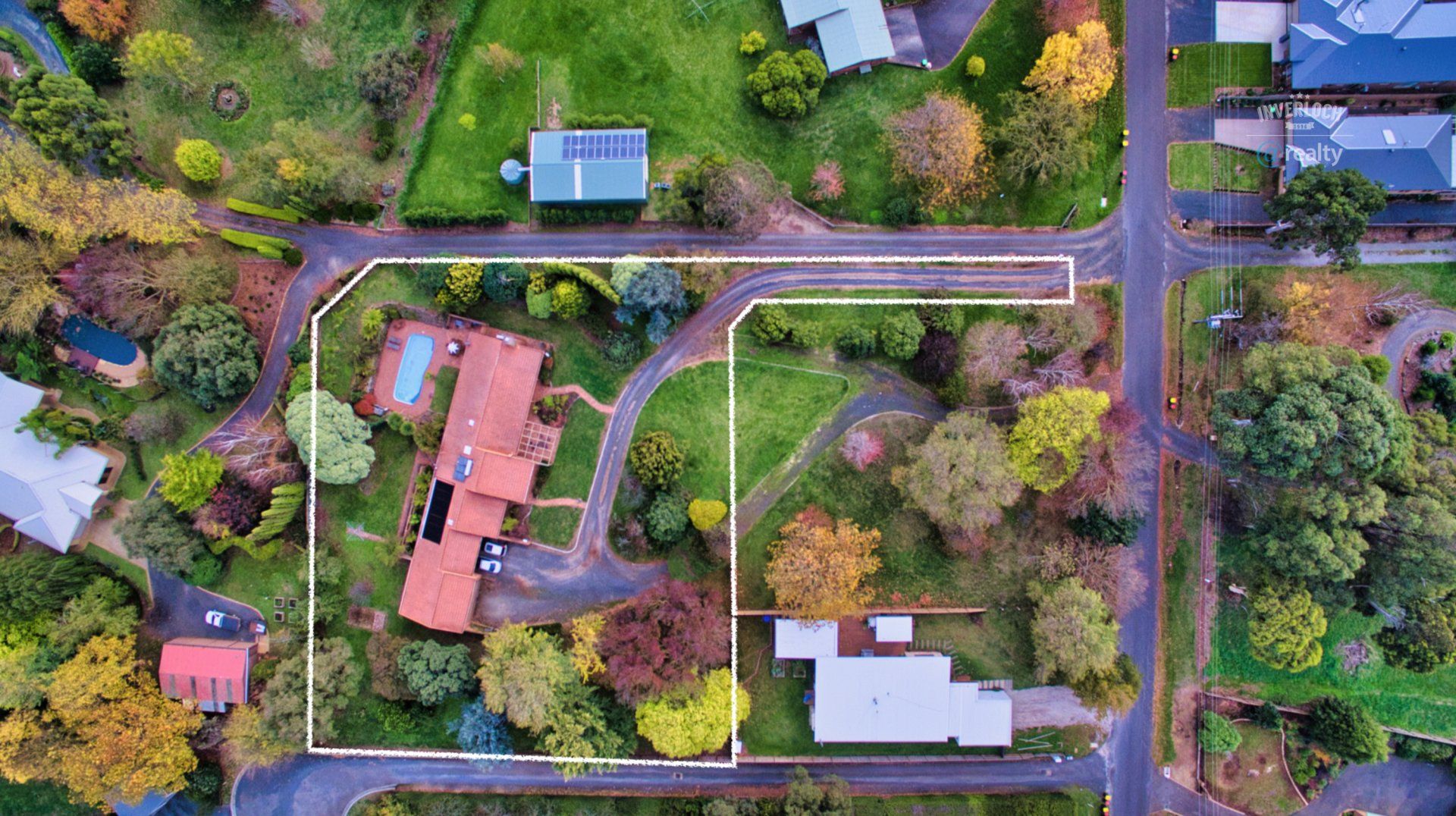 An aerial view of a house in a residential area surrounded by trees and houses.
