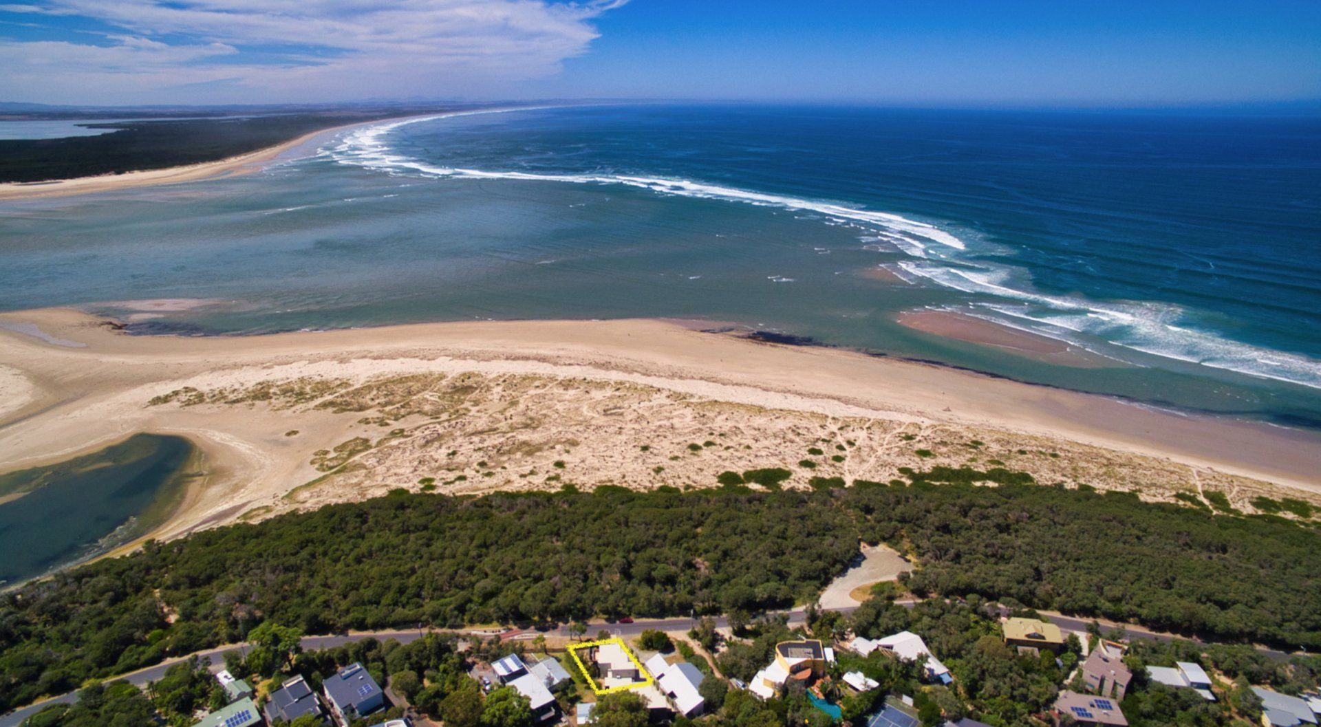 An aerial view of a beach surrounded by trees and a body of water.