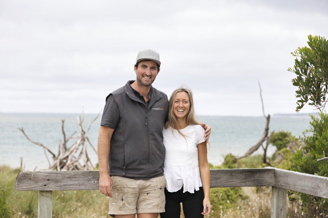 A man and a woman are standing next to each other on a wooden fence.