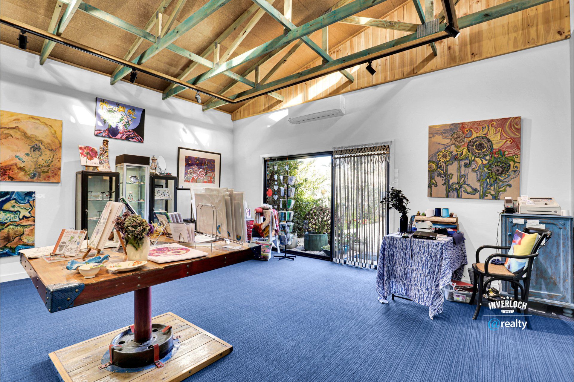 There is a table in the middle of the room with paintings on the wall.