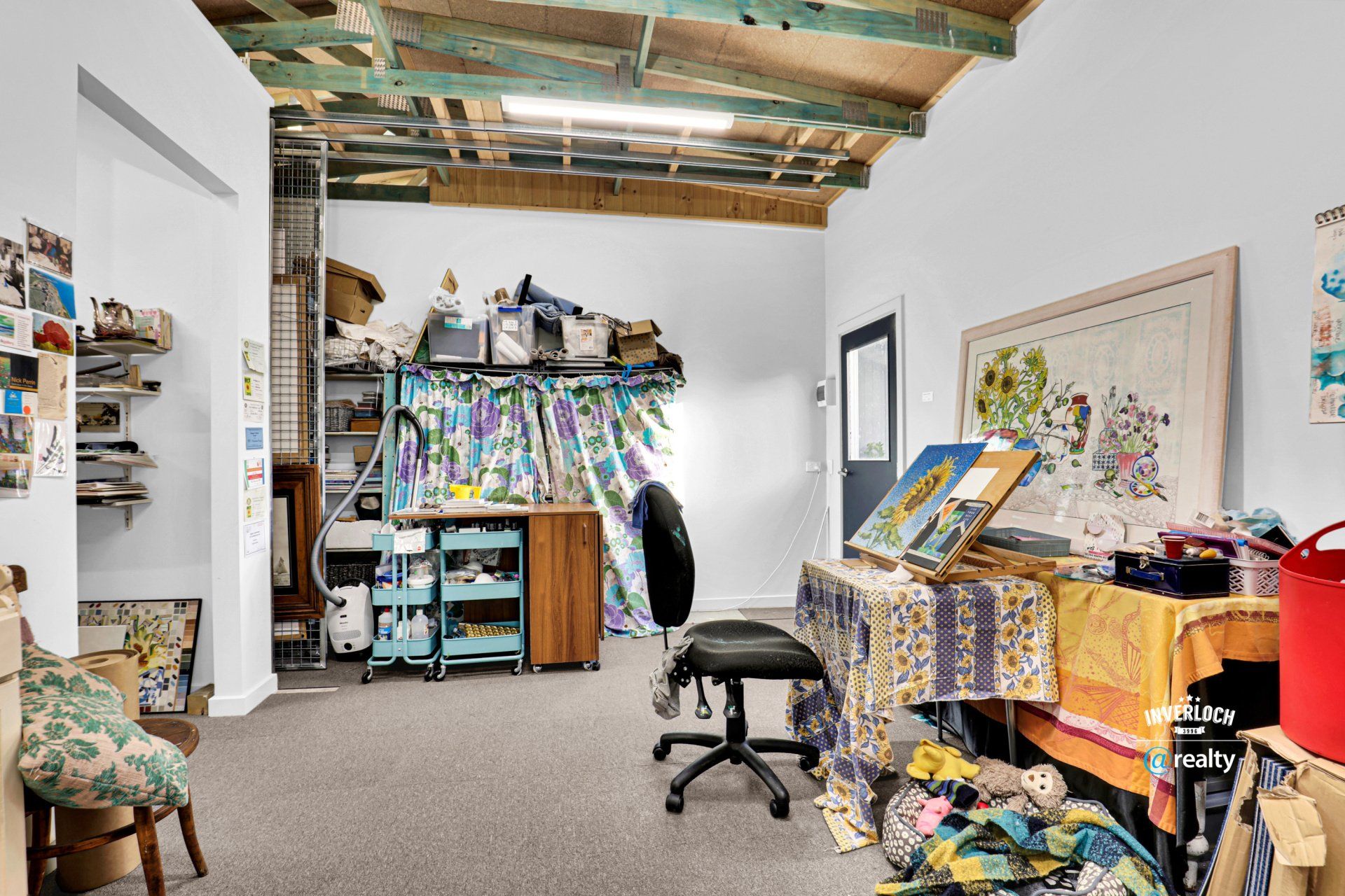 A room with a table and chairs and a table with a painting on it.