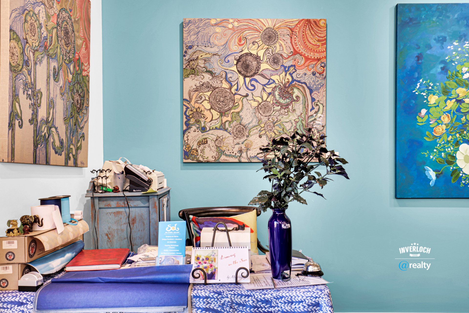 A living room with blue walls and a table with a vase of flowers on it.
