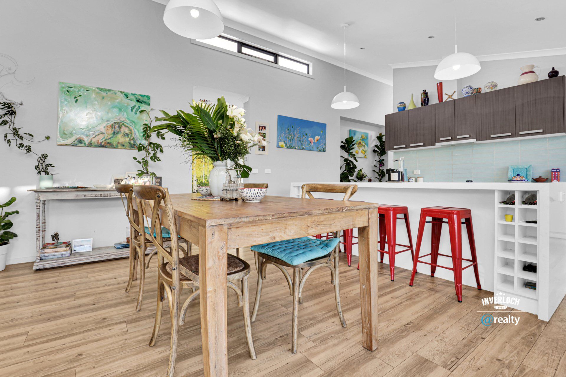 A dining room with a wooden table and chairs and a kitchen.