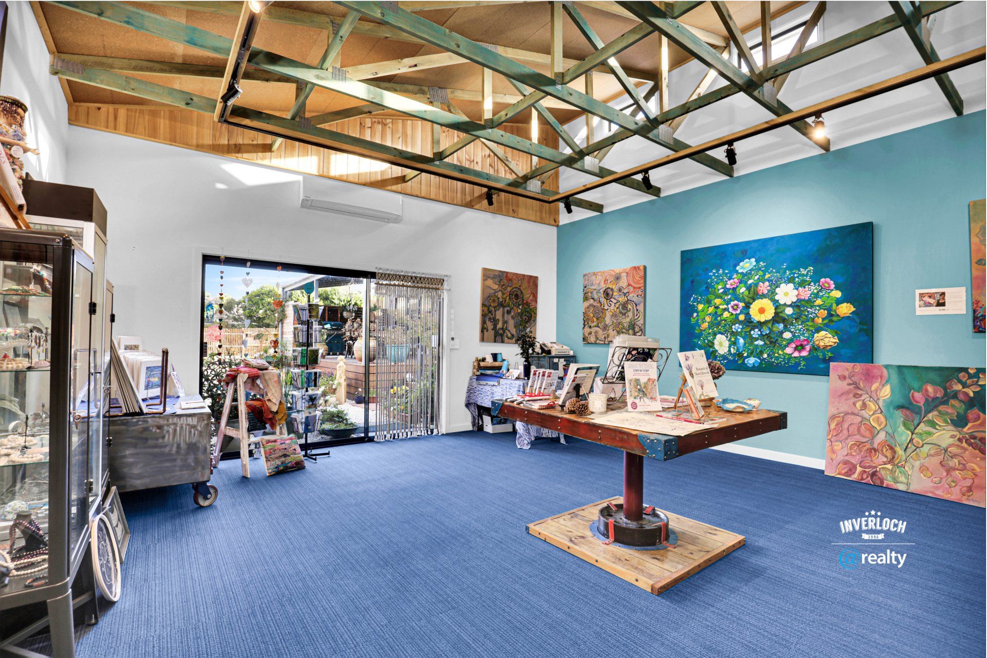 A large room with a table and paintings on the wall.