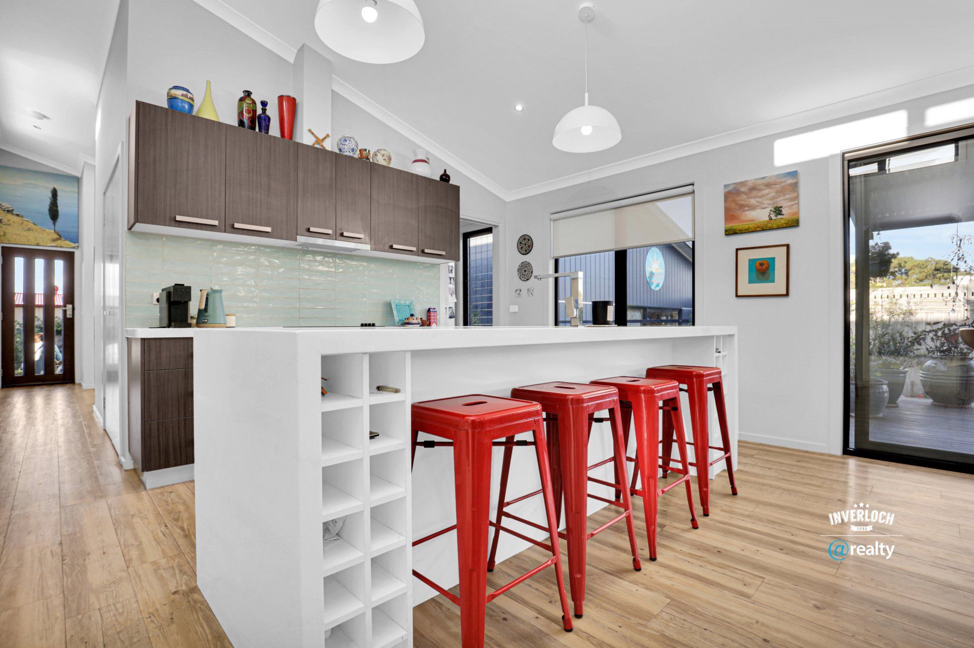 A kitchen with a wine rack and red stools.
