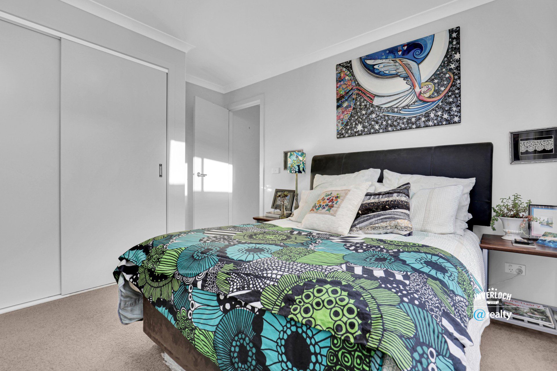 A bedroom with a bed and a painting on the wall.