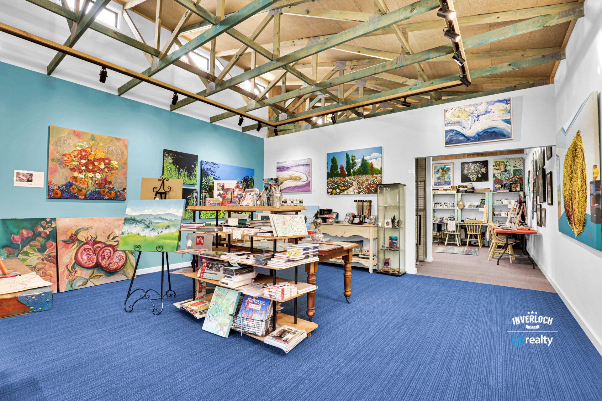 A room with a lot of paintings on the walls and a blue carpet.