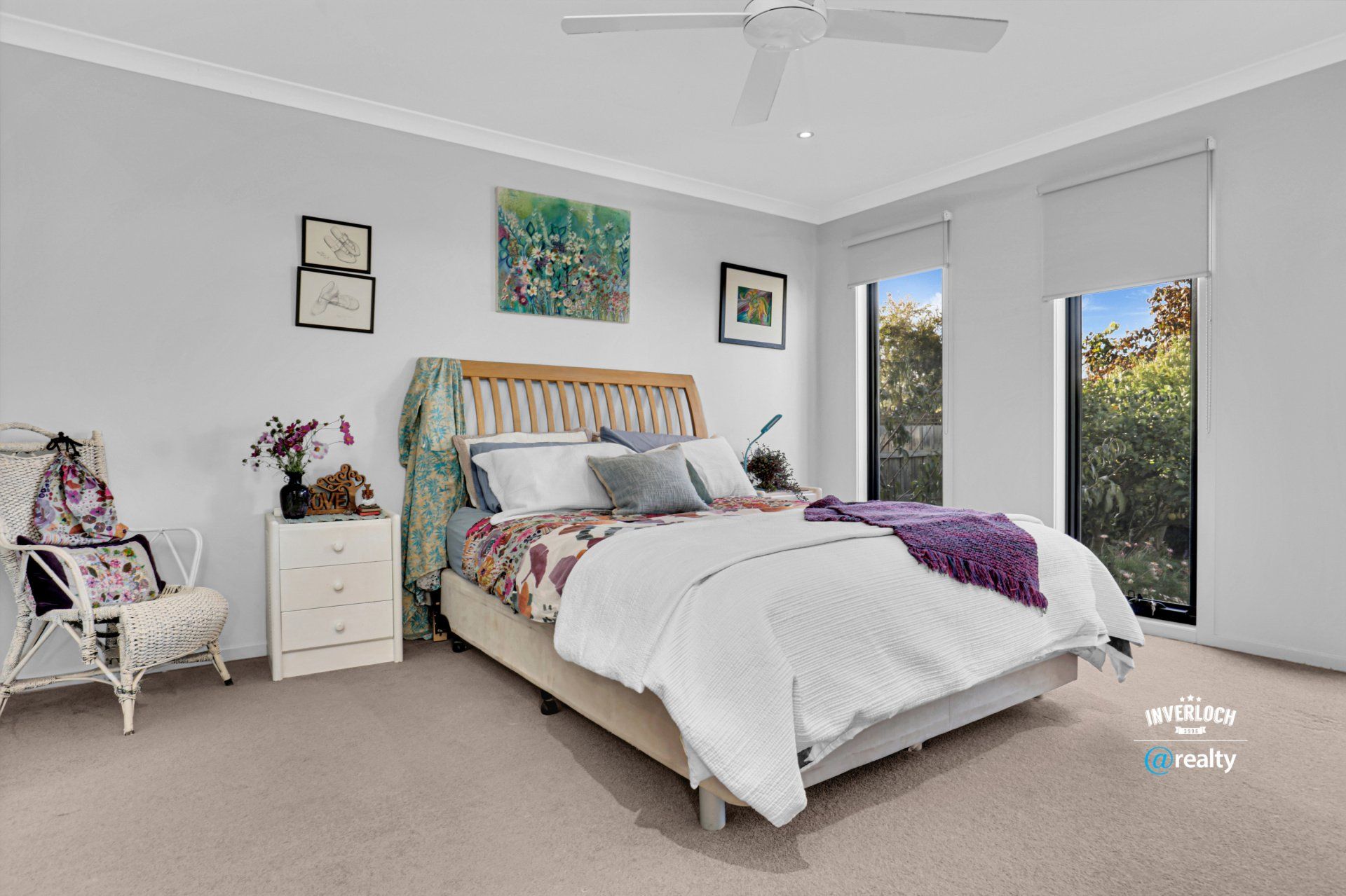 A bedroom with a bed , nightstand , chair and ceiling fan.