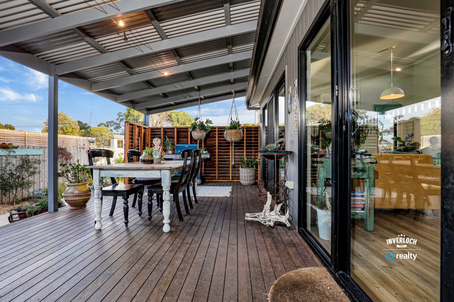 A wooden deck with a table and chairs under a canopy.